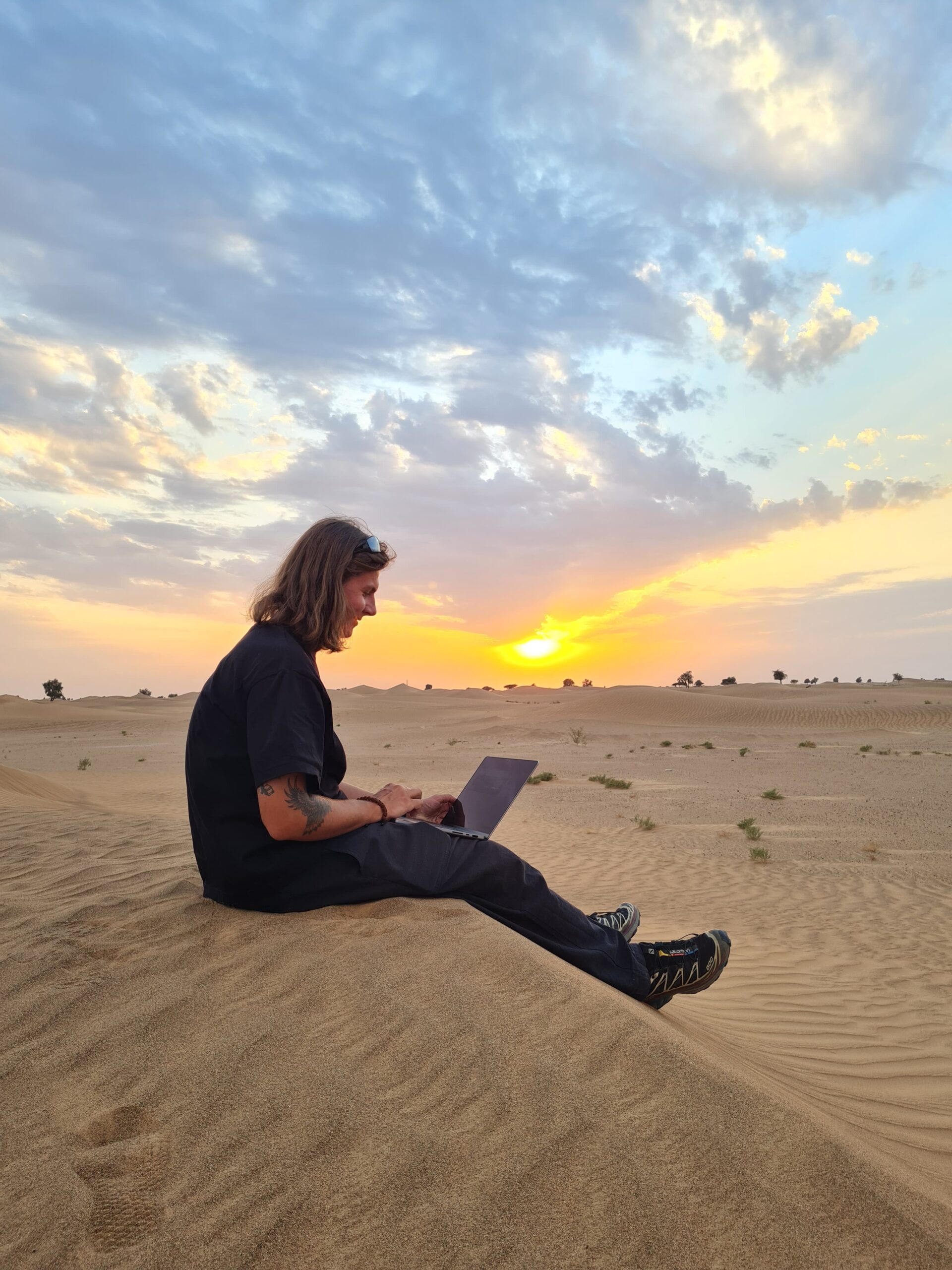 Digital marketeer in de woestijn, werkend op zijn laptop.